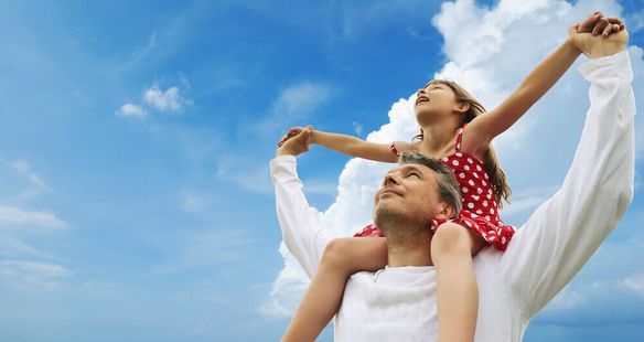 Man with a little girl on his shoulders with a blue sky background