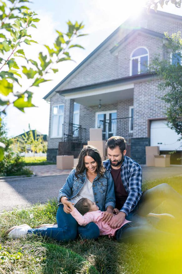 Family sitting in the front lawn of their home