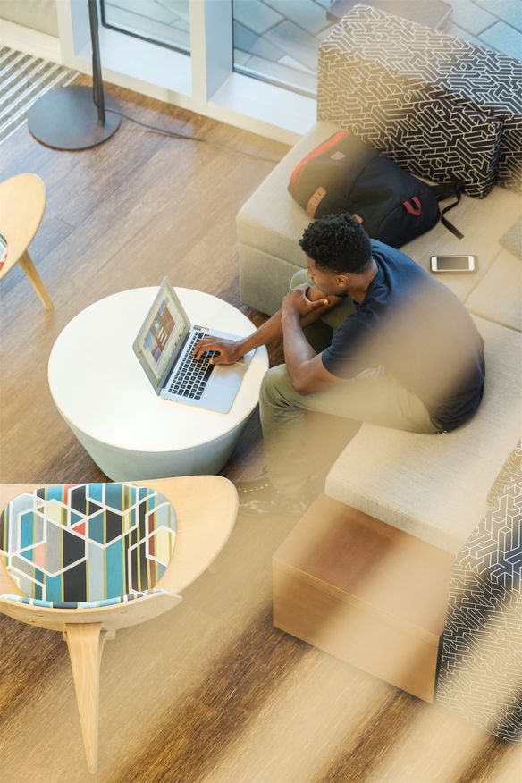 Man sitting on a couch using his laptop