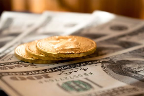 Coins sitting on top of hundard dollar bills spread out